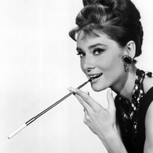 BRAH102 -4046329 Portrait noir et blanc iconique d'Audrey Hepburn dans Diamants sur canapé, posant avec élégance et tenant un long porte-cigarette.
