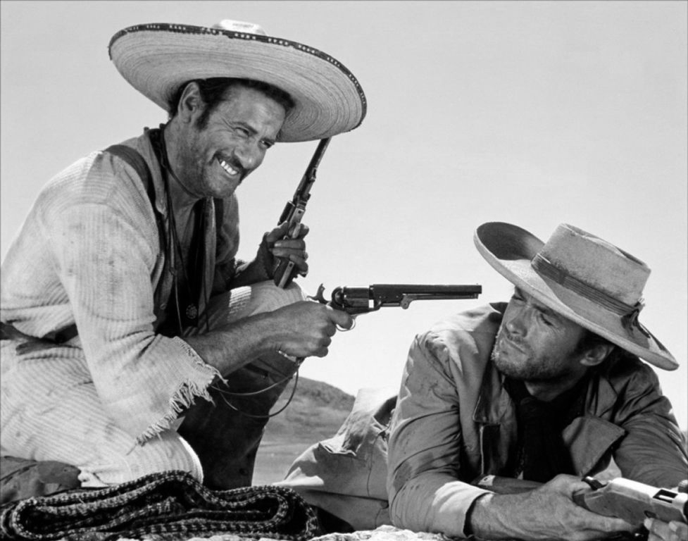 1635504 Le bon, la brute et le truand LE BON, LE BAD ET LE UGGLY Photographie noir et blanc de Eli Wallach pointant un revolver vers Clint Eastwood qui est allongé au sol, scène culte du film Le Bon, la Brute et le Truand.