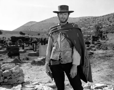 Affiche Eastwood Western Solo : Portrait en noir et blanc de Clint Eastwood debout dans un cimetière, portant son poncho iconique et un chapeau de cowboy, scène du film Le Bon, la Brute et le Truand.