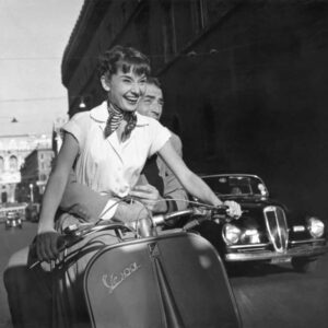 Affiche Audrey Hepburn - Rome : Gros plan en noir et blanc d'Audrey Hepburn riant aux éclats au guidon d'une Vespa, avec Gregory Peck derrière elle, dans une rue de Rome.
