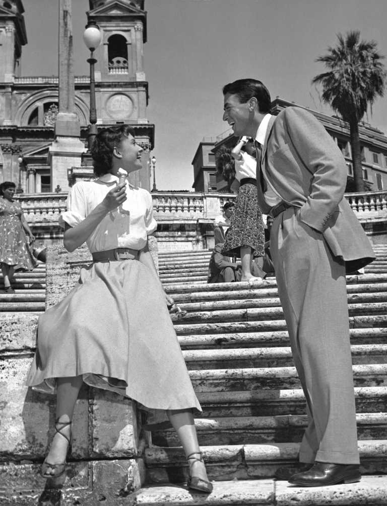 BRHA109 7144116 Photographie en noir et blanc d'Audrey Hepburn mangeant une glace sur les marches de la Place d'Espagne à Rome, face à Gregory Peck qui lui sourit.