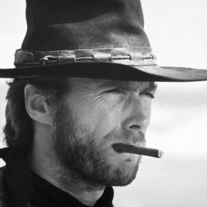 CL35 Portrait serré en noir et blanc de Clint Eastwood en cowboy, portant un chapeau et un cigare aux lèvres, le regard plissé vers l'horizon.