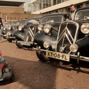 Citroën Traction Avant Paris-Moscou 1984 Affiche publicitaire vintage colorisée de 1984 montrant la Citroën Traction Avant n°116 en pleine course sur une piste de terre boueuse en Russie, acclamée par la foule, sous un ciel nuageux. Titres "PARIS-MOSCOU '84" et "CITROËN TRACTION AVANT".