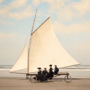 L'Appel du Large : Char à Voile Belle Époque Photographie historique colorisée d'un char à voile ancien sur une plage immense. Quatre passagers élégants en costumes de la Belle Époque sont installés sous la grande voile blanche.