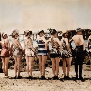 Les Baigneuses (1920) : Charme & Années Folles | Fuzars Photographie vintage colorisée de 1920 montrant huit femmes en maillots de bain rétro alignées sur la plage et regardant par-dessus leur épaule.