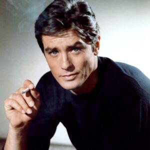 affiche couleur portrait d'Alain Delon dans le film Mélodie en sus soul, il porte un pull noir, regarde l'objetcif et tient une cigarette dans la main droite, il y a des volutes de fumée autour de lui