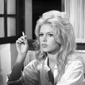 Portrait en noir et blanc de Brigitte Bardot en 1962, portant une chemise rayée et tenant une cigarette, avec un regard mélancolique et sa coiffure blonde signature.