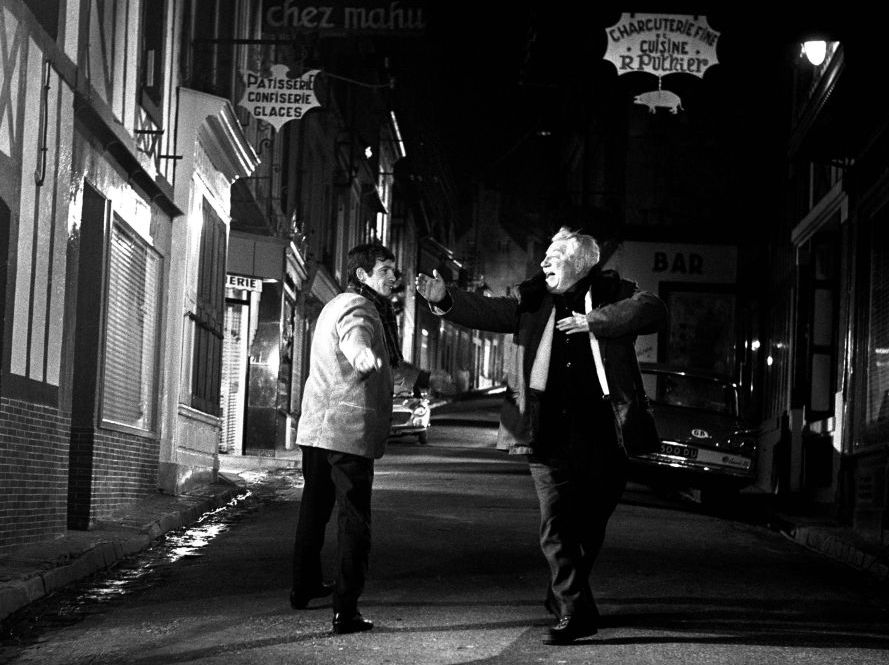 BRJG101 - 2025604 Jean Gabin les bras grands ouverts mimant un toreador face à Jean-Paul Belmondo dans une rue la nuit, scène joyeuse du film Un Singe en Hiver.