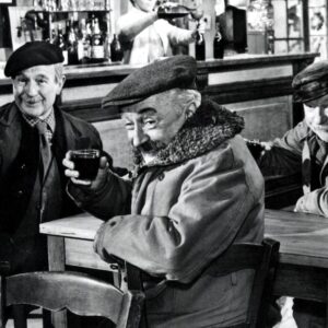 Jean Gabin, Pierre Fresnais et Noël-Noël, portant des casquettes, riant et buvant du vin rouge attablés dans un bistro, scène du film Les Vieux de la Vieille.