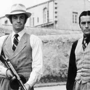 Affiche noir et blanc du film Borsalino montrant Jean-Paul Belmondo avec un chapeau et une mitraillette aux côtés d'Alain Delon en costume 3 pièces