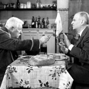 Affiche en noir et blanc du film Le Tatoué avec Louis de Funès et Jean Gabin attablés dans une cuisine rustique
