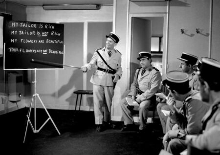 Affiche en noir et blanc du film Le Gendarme à New York avec Louis de Funès donnant une leçon d’anglais à ses collègues gendarmes