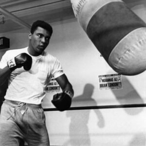 Affiche Mohamed Ali : photographie vintage en noir et blanc de Mohamed Ali s'entraînant avec un sac de frappe en 1966 à Londres.