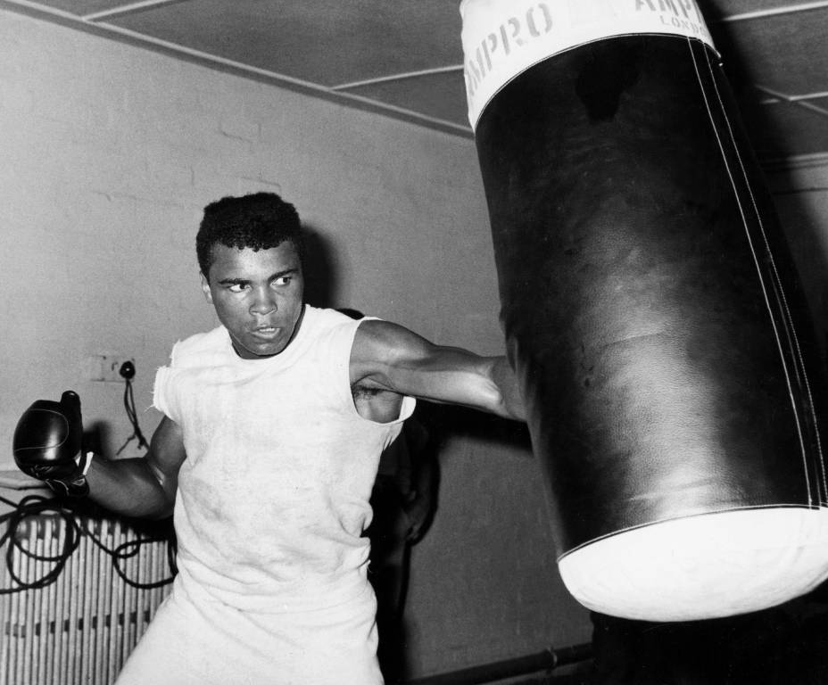 BRMALI103 - 2428018 Affiche Mohamed Ali : photographie d'action en noir et blanc de 1963 montrant Mohamed Ali (Cassius Clay) portant un coup puissant dans un sac de frappe historique "Ampro London" en cuir.