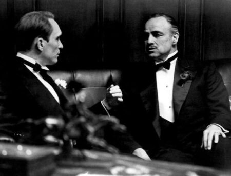 Affiche Brando/Duvall - Parrain : Photo noir et blanc du film Le Parrain (1972) montrant Marlon Brando (Vito Corleone) et Robert Duvall (Tom Hagen) en smoking, discutant avec intensité dans un bureau sombre.
