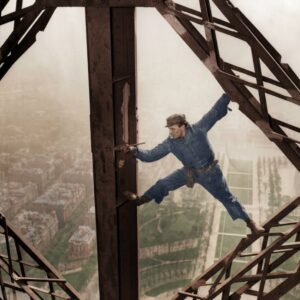 L'Acrobate de 1953 : Le Peintre de la Tour Eiffel | Fuzars Photographie historique colorisée de 1953 montrant un peintre en bâtiment en équilibre sur la structure de la Tour Eiffel, un pinceau à la main, surplombant Paris.
