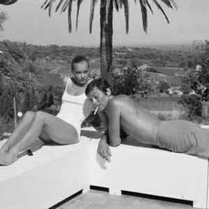 Photographie noir et blanc vintage d'Alain Delon et Romy Schneider en maillot de bain discutant au bord d'une piscine, ambiance film La Piscine 1969.