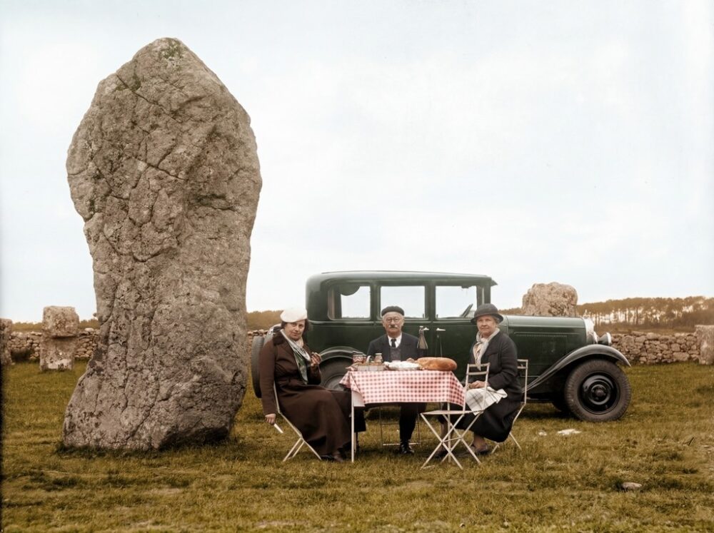 Affiche Carnac 1930 : Menhirs & Élégance Bretonne (Colorisée) | Fuzars Photo colorisée des alignements de menhirs de Carnac en Bretagne vers 1930. Un groupe de personnes pose près des mégalithes et d'un panneau "PROPRIÉTÉ DE L'ÉTAT".
