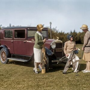 Photographie historique colorisée des années 1920 montrant trois femmes élégantes en tenue de golf discutant près d'une voiture d'époque bordeaux dans un paysage de campagne.