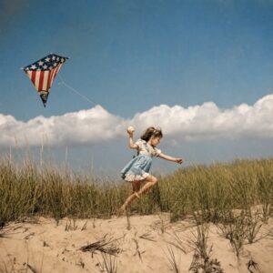 Affiche Cerf-Volant Vintage Plage : photographie d'art colorisée des années 50 montrant une petite fille courant dans les dunes avec un cerf-volant aux couleurs du drapeau américain sous un ciel d'été parsemé de nuages.