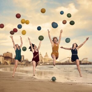 Affiche Plage Vintage Joie : photographie d'art des années 30 montrant quatre femmes en maillot de bain sautant de joie sur une plage avec des ballons.