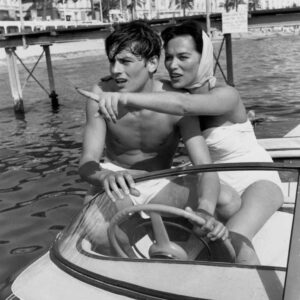 BRADEL106 1653356 Affiche Alain Delon Cannes : photographie d'art en noir et blanc de 1958 montrant un jeune Alain Delon torse nu au volant d'un hors-bord avec l'actrice Bella Darvi sur la mer à Cannes.