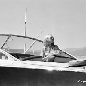 Affiche Brigitte Bardot Riva : photographie vintage en noir et blanc de 1965 montrant Brigitte Bardot pensive à bord d'un bateau Riva Aquarama dans la baie de Saint-Tropez.