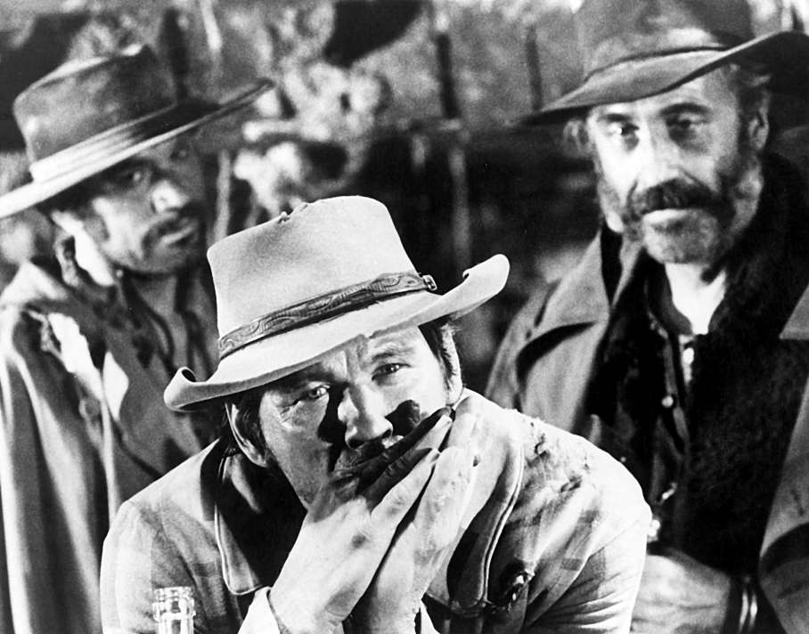 Affiche Charles Bronson Il était une fois dans l'Ouest : photographie d'art en noir et blanc de 1968 montrant Charles Bronson (Harmonica) entouré de deux tueurs dans la scène culte de la gare, ambiance western Sergio Leone.