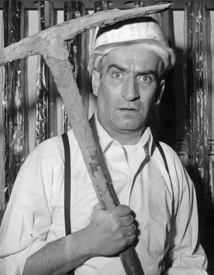 BRLDF106 - 1656833 Affiche De Funès Banque : photographie d'art en noir et blanc de 1964 montrant Louis de Funès avec un casque de chantier et une pioche, tirée du film Faites sauter la banque.