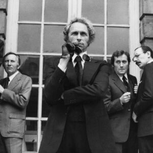 Affiche Le Retour du Grand Blond : photographie d'art en noir et blanc de 1974 montrant Pierre Richard avec des lunettes de soleil, entouré de Jean Rochefort, Michel Duchaussoy et Paul Le Person dans une scène culte d'espionnage.