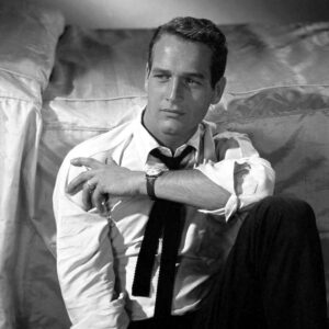 Affiche Paul Newman 1958 : photographie d'art en noir et blanc montrant l'acteur Paul Newman assis, adossé à un lit, portant une chemise blanche déboutonnée et une cravate noire desserrée, regard intense.