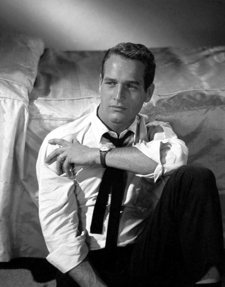 Affiche Paul Newman 1958 : photographie d'art en noir et blanc montrant l'acteur Paul Newman assis, adossé à un lit, portant une chemise blanche déboutonnée et une cravate noire desserrée, regard intense.