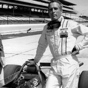 Affiche Paul Newman Virages 1969 : photographie d'art en noir et blanc montrant Paul Newman en combinaison de pilote automobile "Frank", debout à côté d'une voiture de course sur un circuit, ambiance sport mécanique vintage.