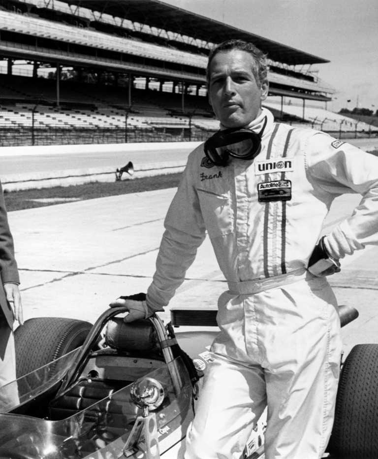 Affiche Paul Newman Virages 1969 : photographie d'art en noir et blanc montrant Paul Newman en combinaison de pilote automobile "Frank", debout à côté d'une voiture de course sur un circuit, ambiance sport mécanique vintage.