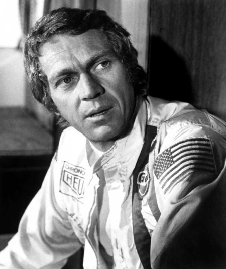 Affiche Pilote Steve McQueen : portrait en noir et blanc de Steve McQueen en tenue de course officielle, portant les logos Gulf et Heuer, capturé en 1971 sur le circuit de la Sarthe.