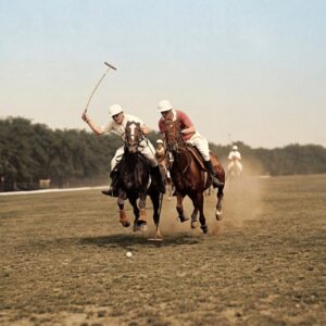 Affiche Polo Vintage Sport : photographie d’art colorisée vers 1935 montrant deux joueurs de polo en pleine action sur leurs chevaux au galop, maillet levé dans un nuage de poussière sur un terrain de gazon.