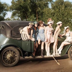 Photographie vintage colorisée des Années Folles représentant un groupe de jeunes femmes élégantes en maillots de bain d'époque posant devant une automobile ancienne, dans un parc ensoleillé.